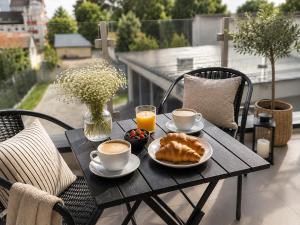 a table with two cups of coffee and pastries on a balcony at SILK Apartman -free private garage in Nyíregyháza +11 photos