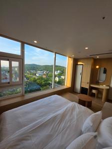 a bedroom with a large white bed with a large window at Mare Suite Hotel in Incheon +79 photos
