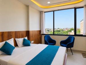 a bedroom with a bed and two chairs and a large window at Hotel Shree Vrindavan Inn in Vrindāvan