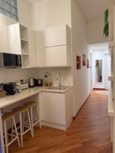 a kitchen with white cabinets and wooden floors at 7 CENTRALE Rooms & Suite in Milan