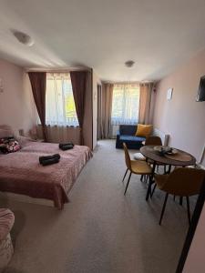 a bedroom with a bed and a table and a couch at MVS Borovetz Gardens Apart E28 studio in Borovets