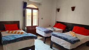 a room with three beds and a window at sunset guest house in Aswan