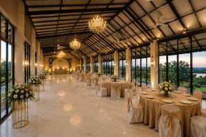 a banquet hall with white tables and chairs and chandeliers at Rivora Villa in Nashik