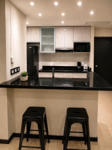 a kitchen with a black counter and two stools at Gran Propiedad en Guayaquil in Guayaquil
