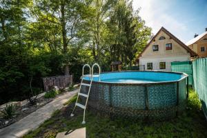 a swimming pool with a ladder next to a house at Ubytování Pod Mostem in Broumov
