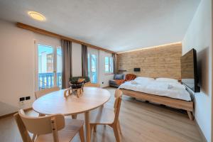 a bedroom with a bed and a table and a couch at Freestyle Alpine Design-Studios - Pool, Parking & Balcony in Center Laax by BlueHills Vacations in Laax