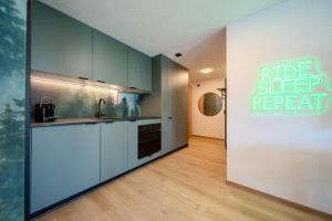 a kitchen with blue cabinets and a sign that reads ride sleep repeat at Freestyle Alpine Design-Studios - Pool, Parking & Balcony in Center Laax by BlueHills Vacations in Laax