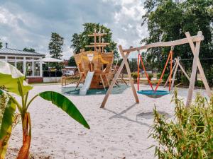 a playground with a swing in the sand at Hotel Bloemfontein in Borkum
