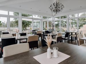 a restaurant with tables and chairs and windows at Hotel Bloemfontein in Borkum
