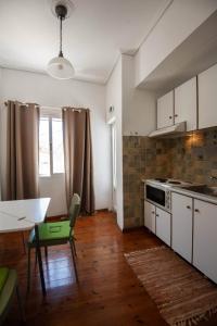a kitchen with white cabinets and a table and a dining room at Chris' Samos Home in Samos