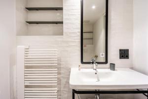 ein weißes Badezimmer mit Waschbecken und Spiegel in der Unterkunft Brera Serviced Apartments Munich Schwabing in München
