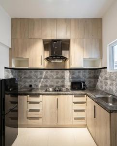 a kitchen with wooden cabinets and a black refrigerator at Hamsun Apart Hotel Clifton in Karachi