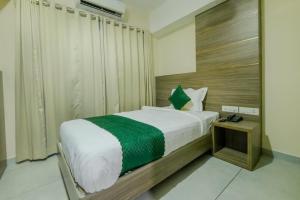 a bedroom with a bed with a green and white blanket at The Heartland Business Hotel in Trivandrum