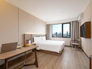 a hotel room with a bed and a desk with a laptop at Model J Hotel Jakarta Central Park 曼居酒店 雅加达中央公园店 in Jakarta +58 photos
