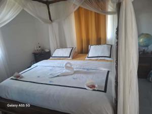 a bedroom with a bed with two swans on it at Villa TSARAJORO in Toamasina +5 photos
