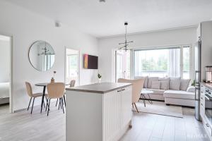 a white kitchen and living room with a table and chairs at Modern two-bedroom apartment in Espoo