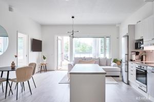 a white kitchen and living room with a couch and a table at Modern two-bedroom apartment in Espoo