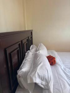 an unmade bed with white sheets and an orange object on it at Sunrise Suites EMBU in Embu