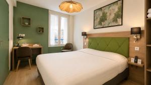 a bedroom with a white bed and a desk and a table at Logis Hôtel Au Croissant in Buzançais