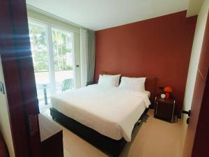 a bedroom with a large bed and a large window at Syama Mansion Kamala in Kamala Beach