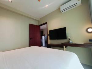 a bedroom with a white bed and a flat screen tv at Syama Mansion Kamala in Kamala Beach