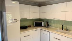 a kitchen with white cabinets and a microwave at Urla Sunrise House in Ildır +26 photos