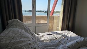 an unmade bed in a bedroom with a window at Zuiderzee State - Appartementen in Makkum