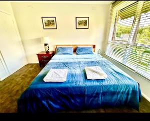 a bedroom with a blue bed with two towels on it at Jalynn homestay in Glen Waverley