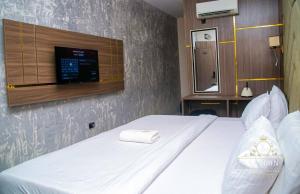 a bedroom with a white bed with a tv on the wall at Laycon hotel and suites in Ikuata