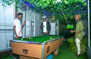 a group of men standing around a pool table at Laycon hotel and suites in Ikuata