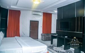 a bedroom with a bed and a television and a couch at Laycon hotel and suites in Ikuata