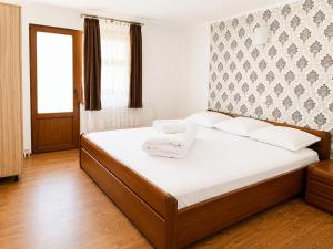 a bedroom with a large bed with white sheets at Pensiunea Hanzu Darius in Gura Râului