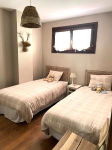 two beds in a bedroom with two stuffed animals on them at Apartamento El Gorgol in Tramacastilla de Tena
