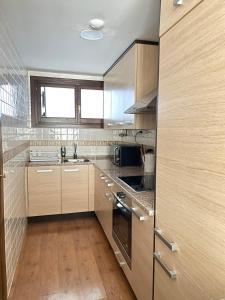 a large kitchen with wooden cabinets and a window at Apartamento El Gorgol in Tramacastilla de Tena
