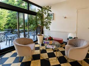 a living room with two chairs and a glass table at Logis Hôtel Au Croissant in Buzançais