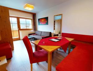 a dining room with a table and red chairs at Landhaus Wildschwendt in Ellmau