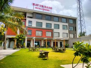 a building with tables and chairs in front of it at Mayur baag resort in Sāgar