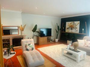 a living room with a white chair and a tv at Anjos’home in Viana do Castelo