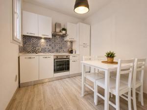 a kitchen with white cabinets and a table and chairs at Il Rifugio di Trip Centro Storico & Lago in Mantova