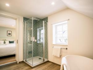 a bathroom with a shower and a bed and a window at Flecker Hotel in Freudenberg