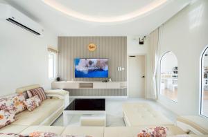 a living room with a couch and a tv at Seahorse poolvilla sattahip SP2 in Ban Nong Sa