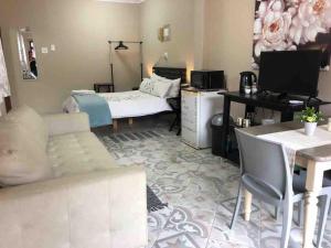 a living room with a couch and a desk and a bed at Meerensee tranquil suite in Richards Bay