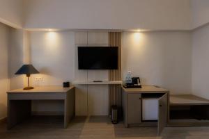 a hotel room with a flat screen tv on the wall at Azana Oasis Hotel Aceh in Luengbata +12 photos