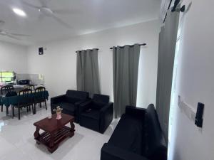 a living room with black couches and a table at AiNi's Homestay in Sipitang