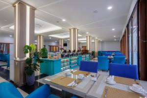 a restaurant with blue chairs and tables and a counter at Azana Oasis Hotel Aceh in Luengbata