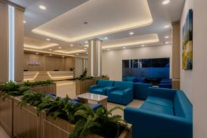 a lobby with blue couches and plants at Azana Oasis Hotel Aceh in Luengbata