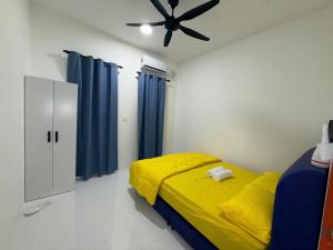 a bedroom with a yellow bed and a ceiling fan at AiNi's Homestay in Sipitang