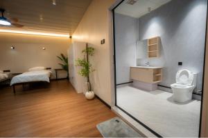 a bathroom with a toilet and a bedroom with a bed at Spacious 5BR Canopy Home with Farm in Kepala Batas