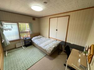 a bedroom with a bed and a desk and a window at EZO HOUSE in Kawayu