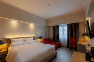 a hotel room with a bed and a red chair at Azana Oasis Hotel Aceh in Luengbata